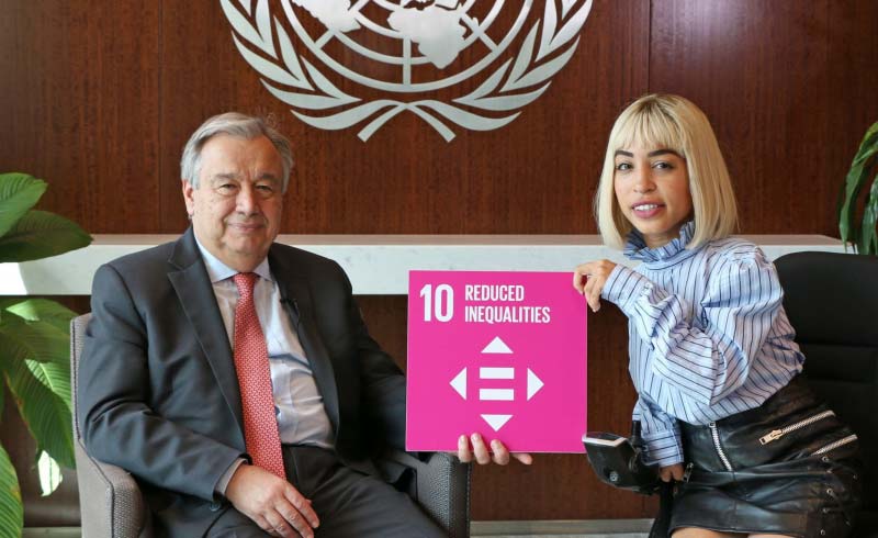 Jillian Mercado och UNs generalsekreterare António Guterres håller tillsammans i en skylt av det tionde målet  ”Reducerade ojämlikheter”.