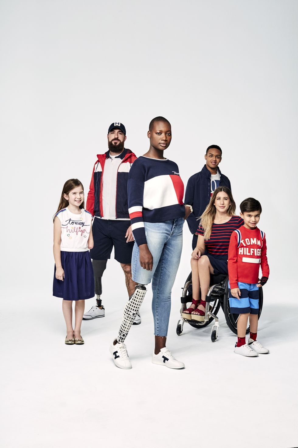 En kampanjbild från Tommy Hilfigers Adaptive kollektion. Sex personer i olika kön, ålder, etnicitet, storlek och funktion har på sig kläder från Tommy Hilfiger i jeans, vitt, marinblått och rött.
