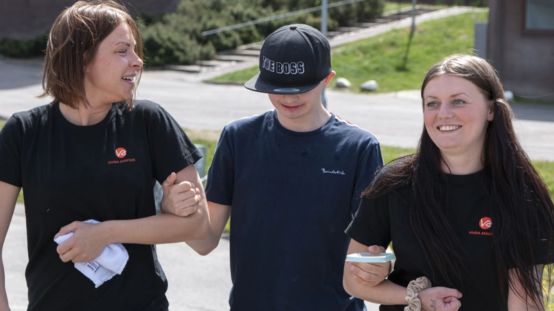Tre personer som går arm i arm bredvid varandra.